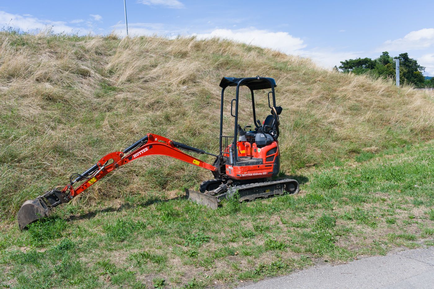 A mini-excavator on a grassy site
